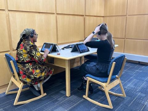 Two library patrons sitting and listening to the digital curation display