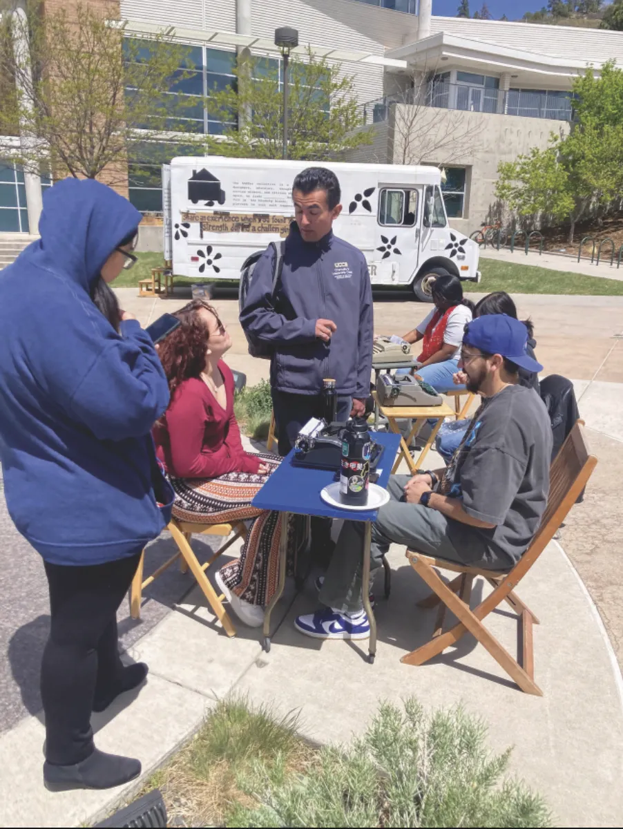 Photo of people congregating around a typewriter